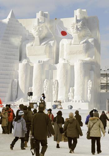 People walk in front of the snow sculptu