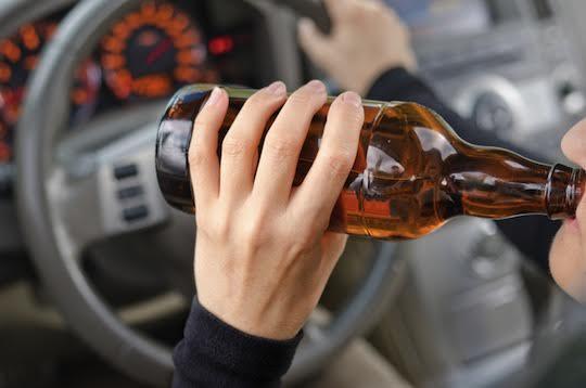 Close up portrait of human drinking alcohol while driving