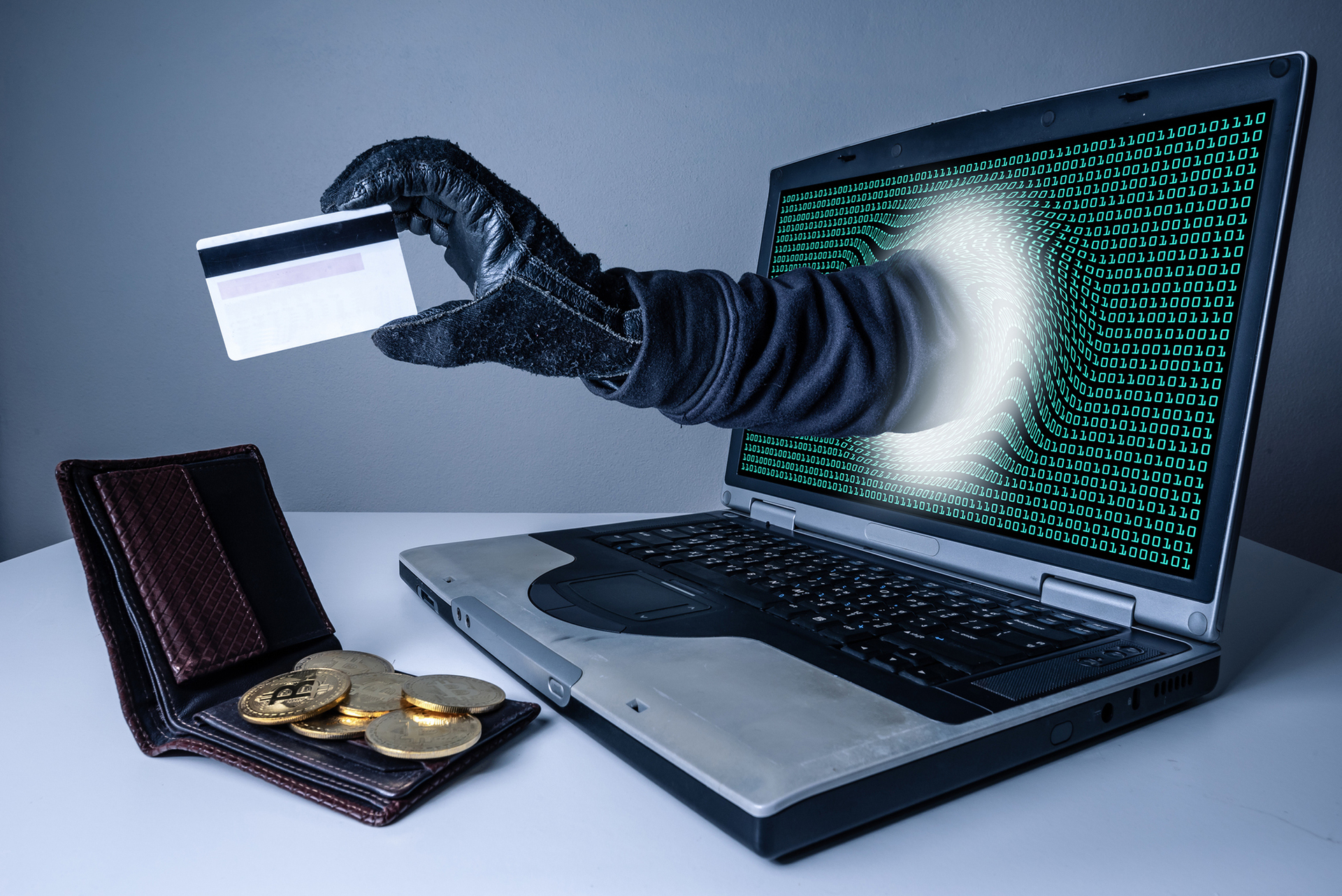 The abstract image of the hacker's hand reach through a laptop screen for stealing credit card in a wallet. the concept of cyber attack, virus, malware, illegally and cyber security.
