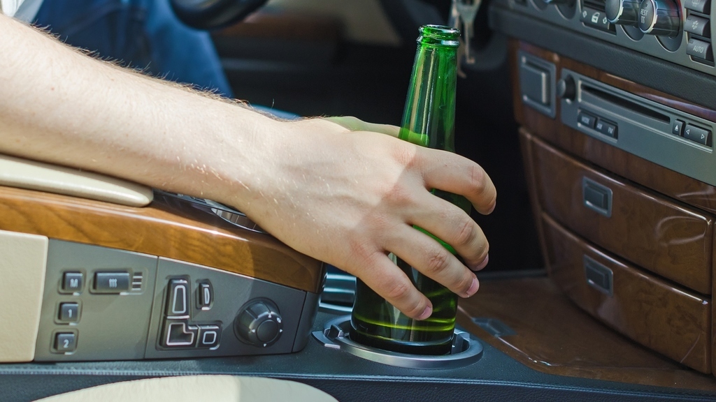 Driving Under the Influence. Male hand with bottle of beer.